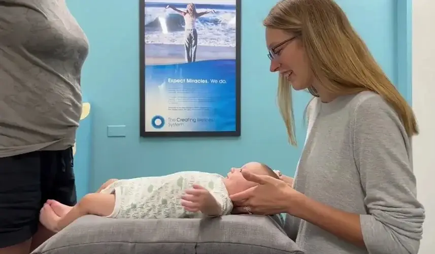 A female chiropractor gently evaluates an infant on a table, showing chiropractic care safe for toddlers naturally.
