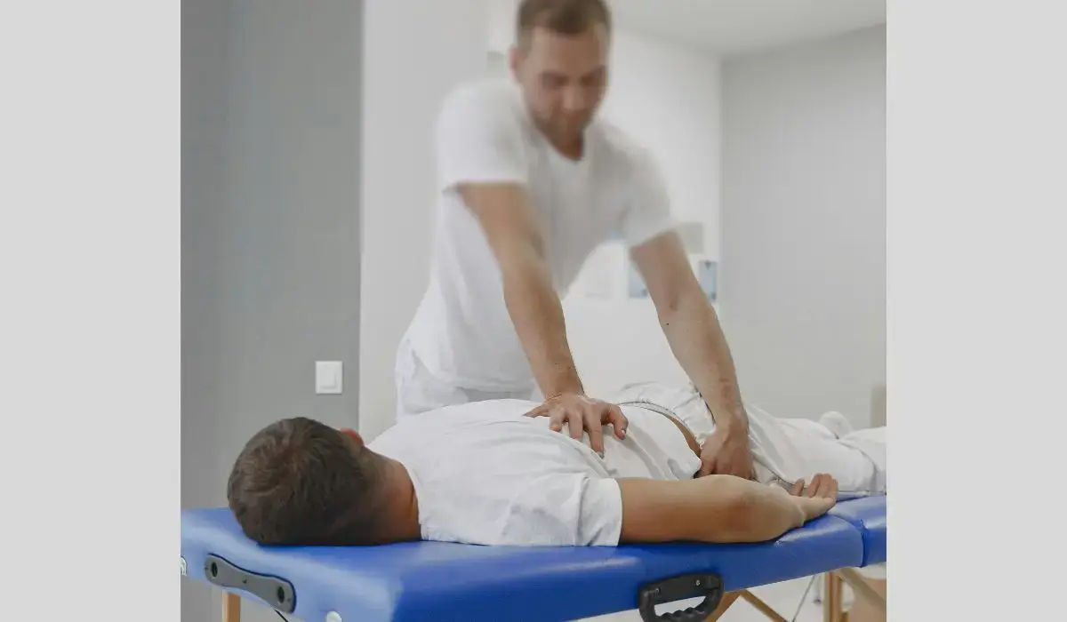 A chiropractor performing a hands-on adjustment on a patient with lower back pain.
