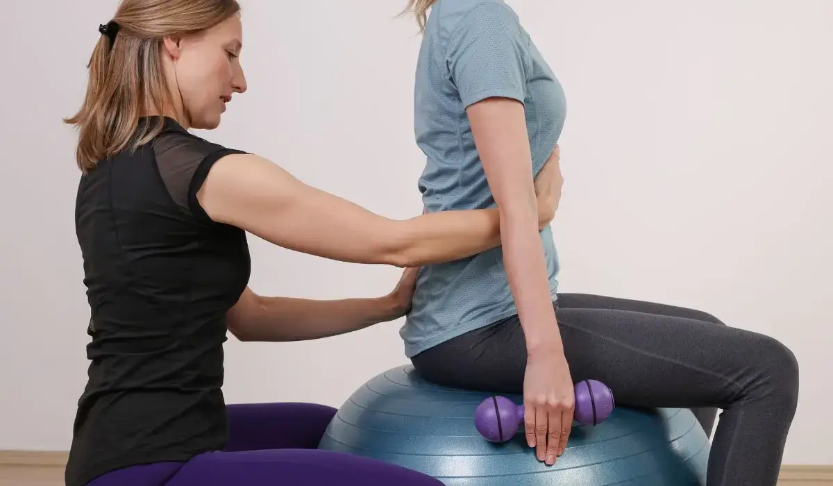 Patient performing spinal posture correction with guided support on a stability ball in chiropractic setting.