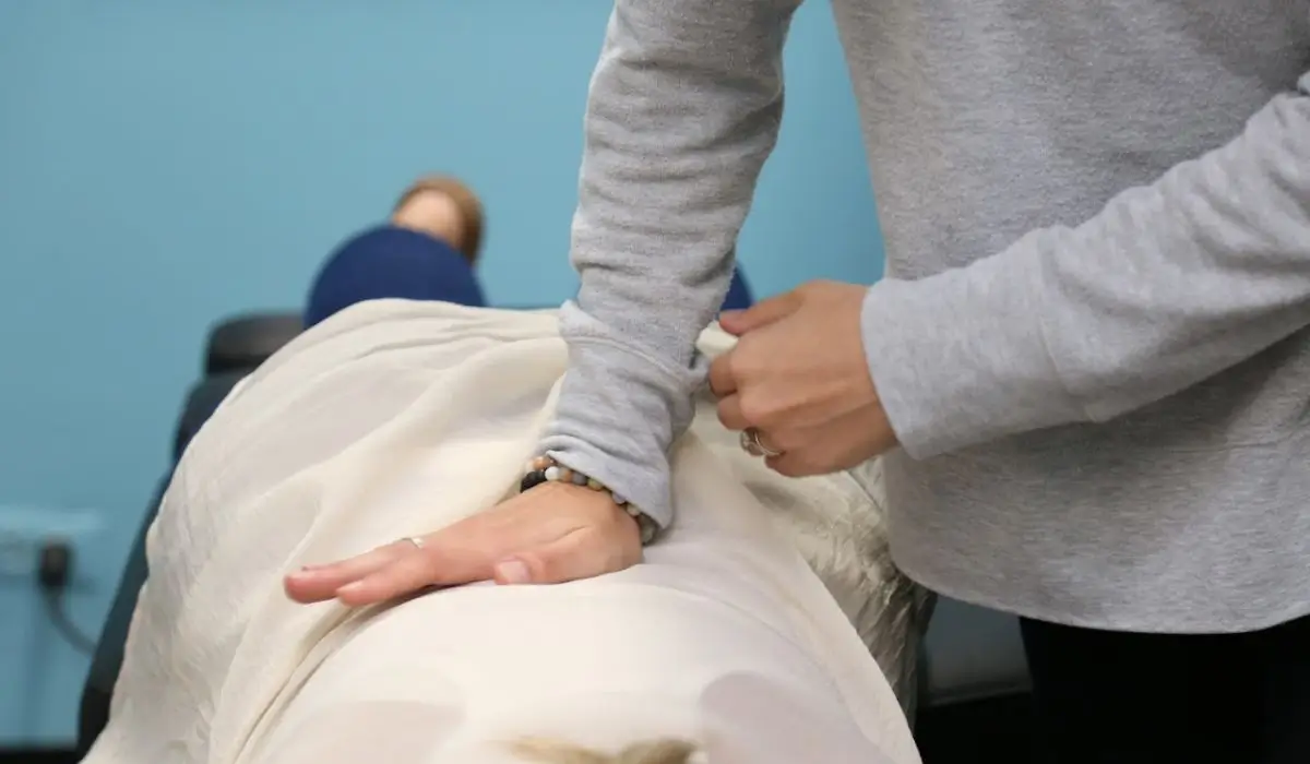 Chiropractor providing gentle spinal adjustment to support patients experiencing abdominal pain and improve overall nervous system function.