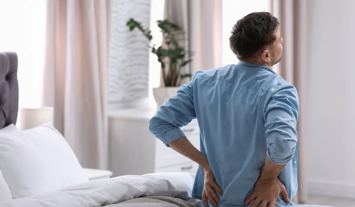 Man waking up with lower back discomfort showing how Joint Pain Affects Sleep and nightly rest quality.