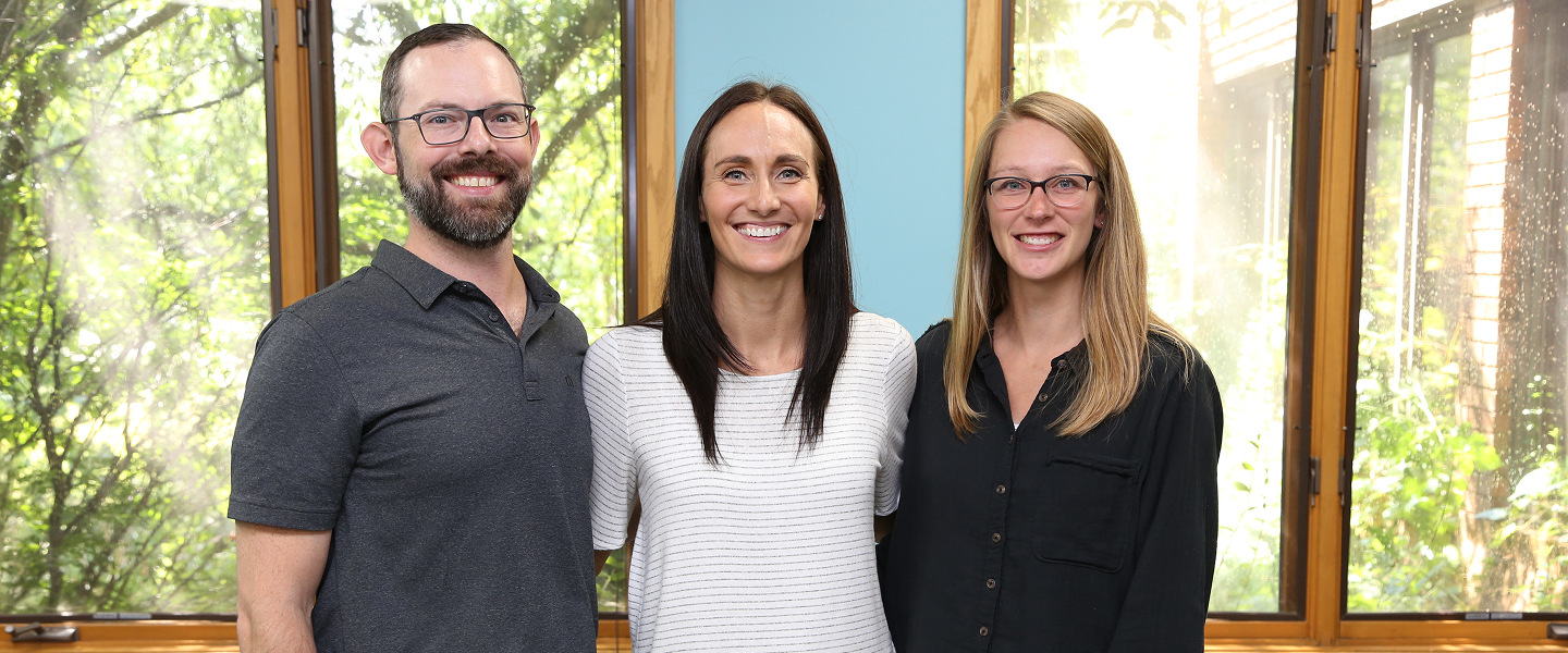 The Sleigh Family Chiropractic team standing together in their clinic, smiling and welcoming patients
