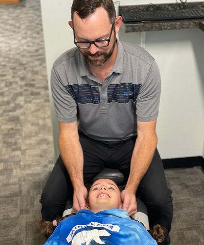 Dr. Quintin Sleigh providing a gentle chiropractic neck adjustment to a young patient