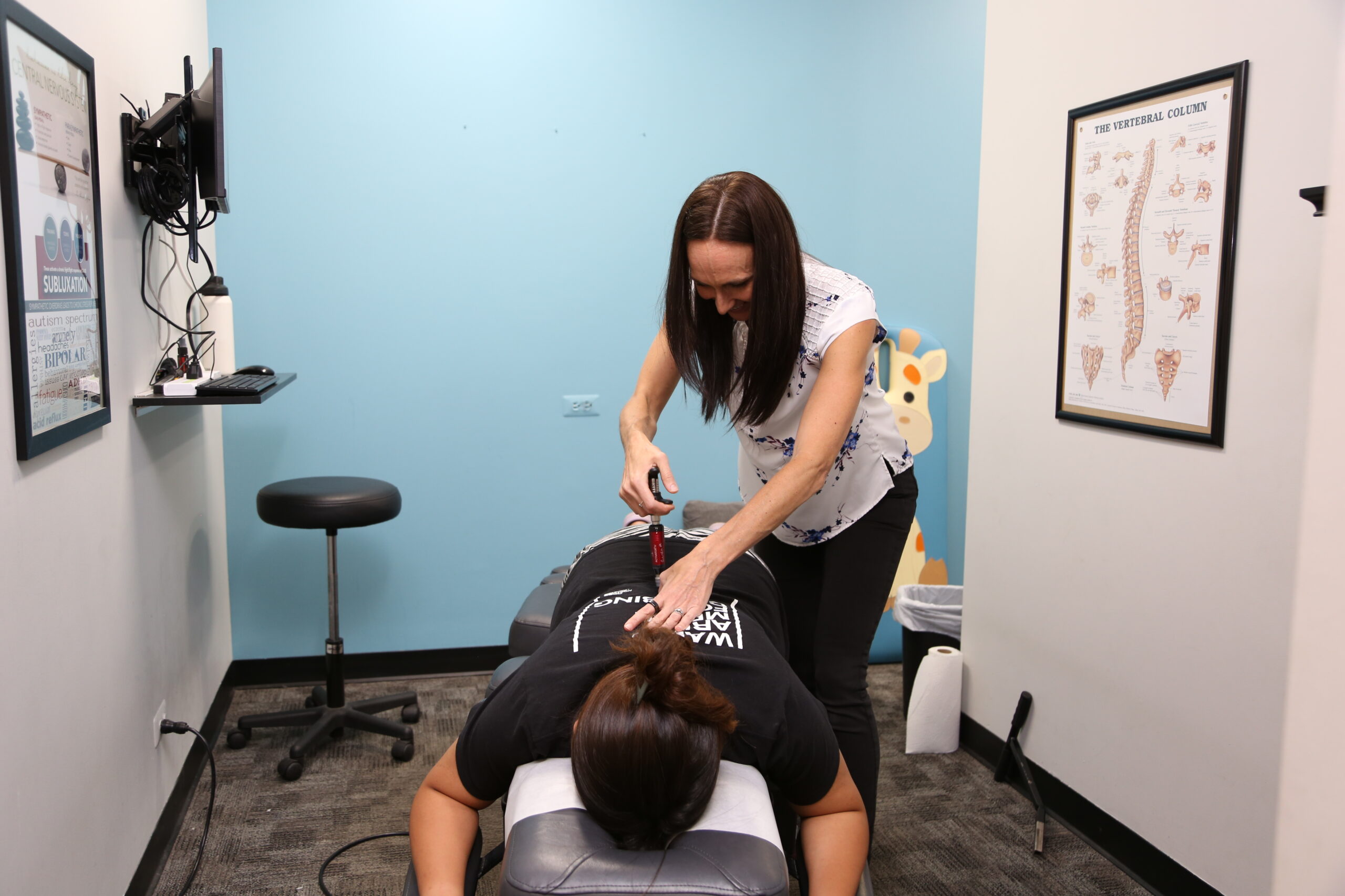 Chiropractor performing an activator tool adjustment on a patient during a chiropractic treatment session