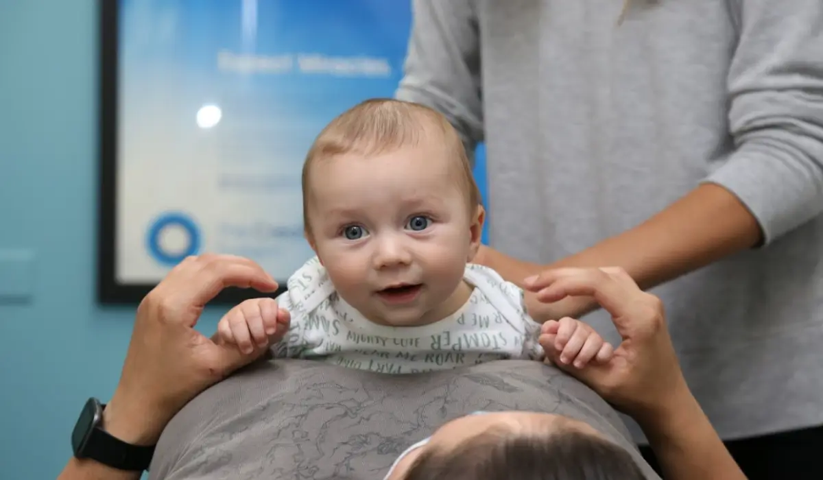 Chiropractic for infants gentle adjustment while baby rests calmly supported by parent during evaluation.