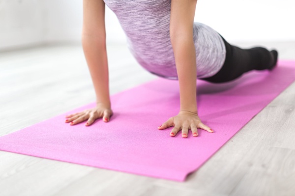 A woman performing a push-up on a pink yoga mat.