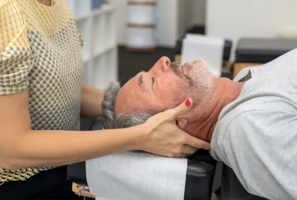 Chiropractor performing gentle neck adjustment on older man, promoting balance and mobility for Arlington Heights seniors.