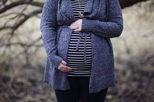 A pregnant woman in a striped cardigan and black leggings