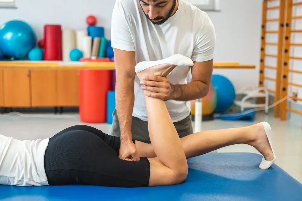 Chiropractor performing a leg mobility adjustment on an athlete during a sports recovery session focused on injury prevention and muscle balance.