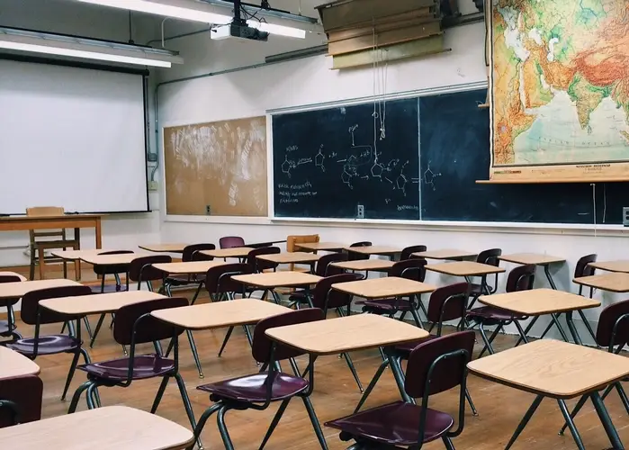A classroom with neatly arranged desks and chairs facing a chalkboard