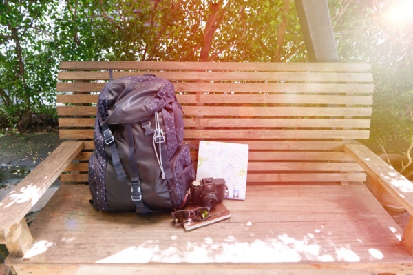 A backpack and camera resting on a wooden bench.