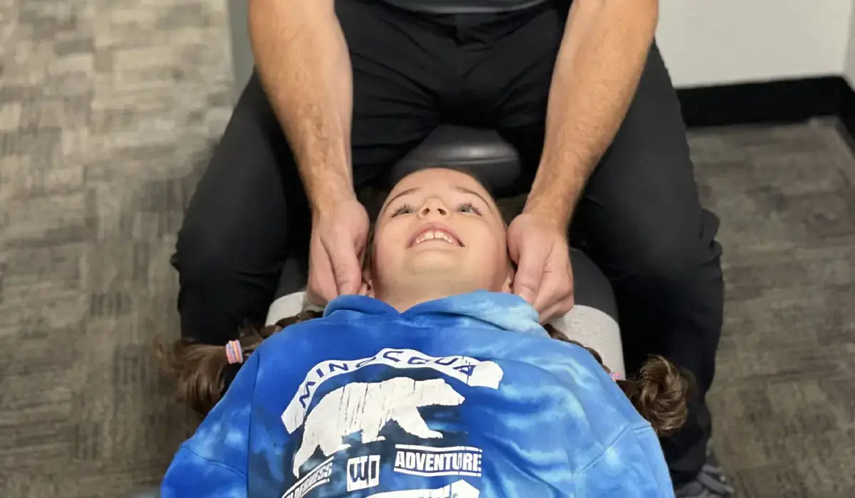 A chiropractor adjusts the neck of a child. Pediatric neck adjustment for neck pain relief.