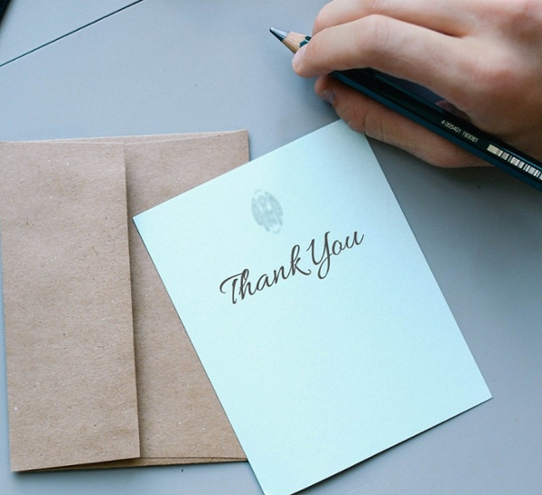 A thank you card with a pen resting on a desk.