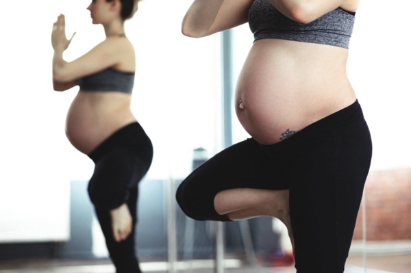 Pregnant woman practicing yoga in a gym.