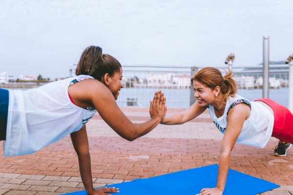 Two women doing push ups on blue mat.